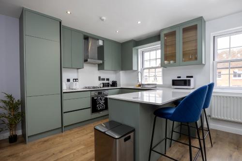 a kitchen with green cabinets and blue bar stools at Stunning 3BR, Free Parking, near Town Center, Long term discoun in Reading