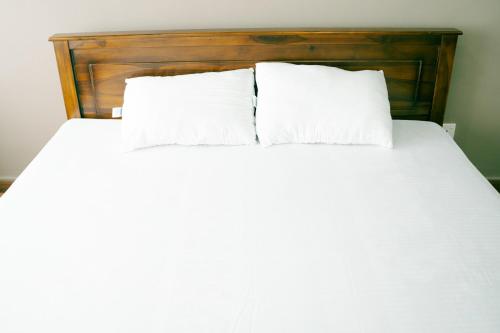 a white bed with two pillows on top of it at Havelock City Hostel, Colombo in Colombo
