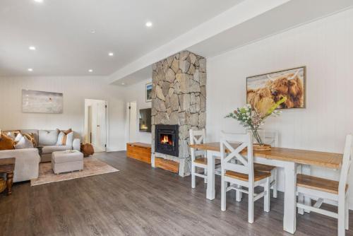 a living room with a table and a fireplace at Nowhere Cottage in Crackenback