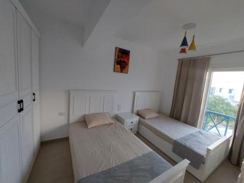 a bedroom with two beds and a window at Villa Mountain View North Coast ماونتن فيو رأس الحكمه in Ras Elhekma