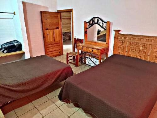 Un dormitorio con dos camas y un escritorio y un espejo. en Cabaña D' Torres, en Mazamitla