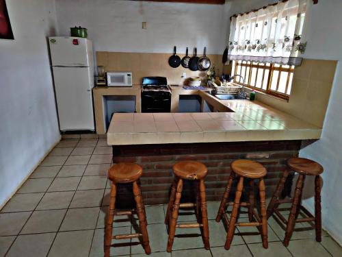 Una cocina con una encimera con taburetes y un refrigerador. en Cabaña D' Torres, en Mazamitla
