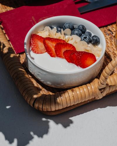 a bowl of yogurt with strawberries and blueberries at Pelican Bay Hotel in Platis Yialos Mykonos