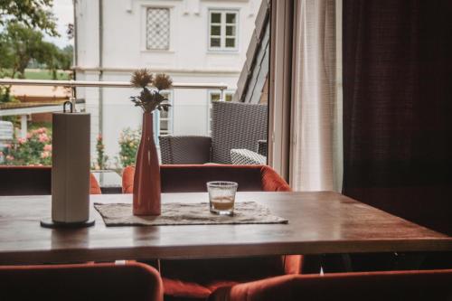 a table with a vase and a glass on it at Gasthaus am Henriettenhof in Grömitz