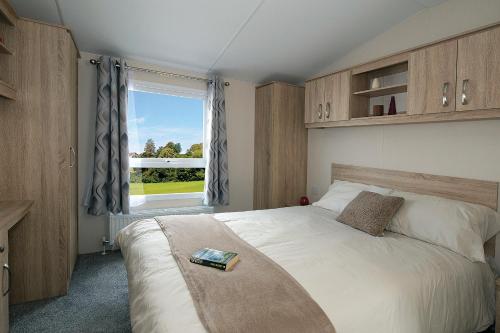 a bedroom with a large bed and a window at Roselands caravan park, Nr Lands End, Cornwall in St. Just