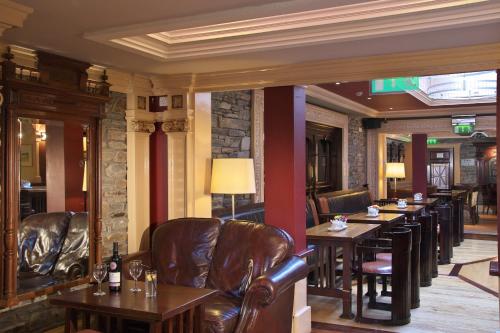a bar with leather chairs and tables in a restaurant at Castle Hotel Macroom in Macroom