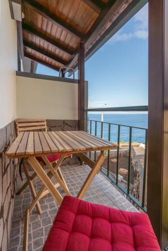 a balcony with a bench and a table and the ocean at Casas das Hortas, Apartamento Vista Serra e Mar in Seixal