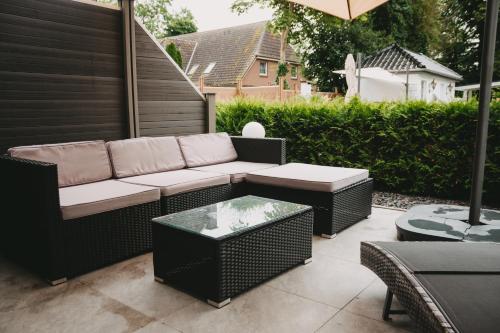 a patio with a couch and tables and an umbrella at Gasthaus am Henriettenhof in Grömitz