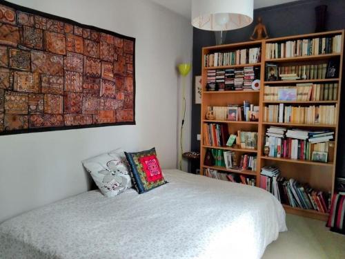 - une chambre avec un lit et une étagère avec des livres dans l'établissement Bel appartement avec terrasse, à Saint-Grégoire