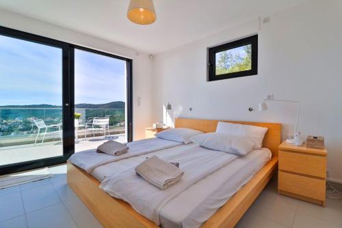 une chambre avec un grand lit avec une grande fenêtre dans l'établissement Modernes Ferienhaus La petite maure mit Pool und wunderschönem Meerblick, familienfreundlich, à Roquebrune-sur Argens