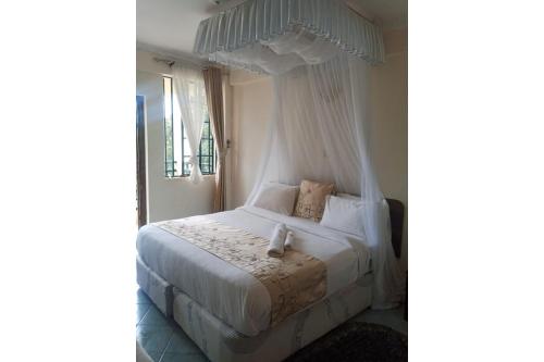 a bedroom with a white bed with a canopy at Parkview Safari Hotel & Apartments in Kisumu