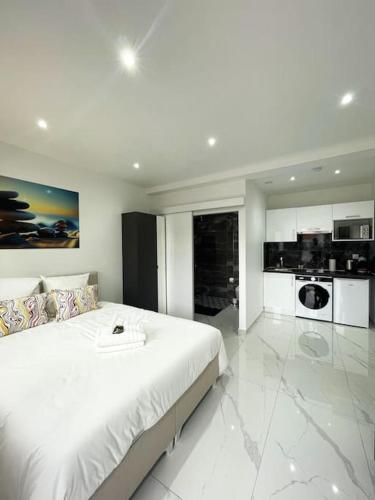 - une chambre blanche avec un grand lit et une cuisine dans l'établissement Moderne Studio proche ORLY- Paris, à Paray-Vieille-Poste