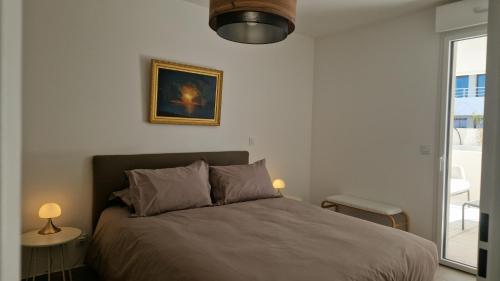 a bedroom with a bed and a picture on the wall at Archipel Coté Jardin in Valras-Plage