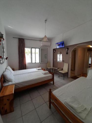 Un dormitorio con dos camas y una mesa y un escritorio. en Iliada, en Skiathos