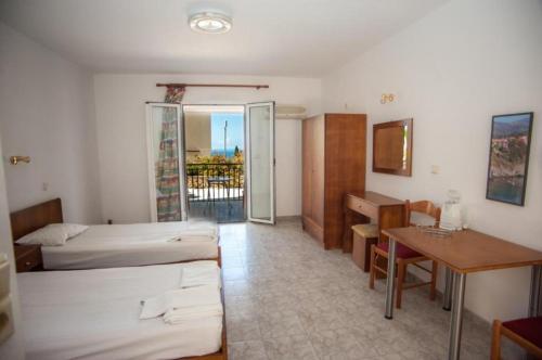 a room with two beds and a desk and a table at Agathaggelos Studios in Vlachata