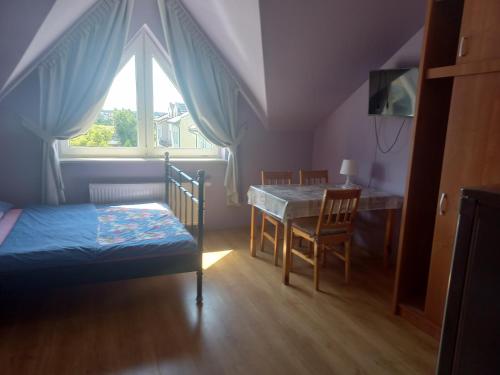 a bedroom with a bed and a table and a window at Robi pokoje i apartament in Łeba