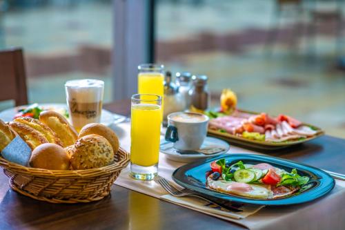 a table with plates of food and two glasses of orange juice at Zsóry Liget Camping & Resort in Mezőkövesd