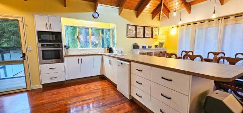 a large kitchen with white cabinets and a wooden floor at Tipani Lodge - Free and Unlimited Wifi in Rarotonga