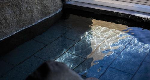 a pool of water on the ground next to a building at Sennenmatsu in Imabari