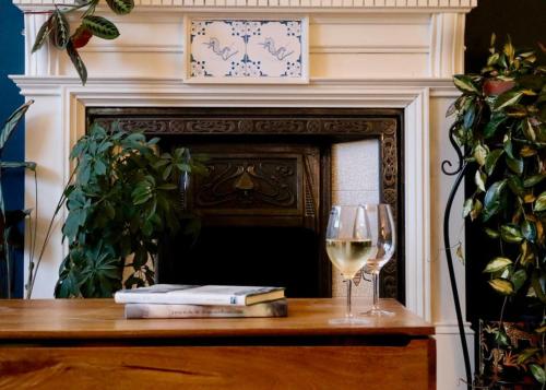 a glass of white wine next to a fireplace at Hyem at Cullercoats in Cullercoats