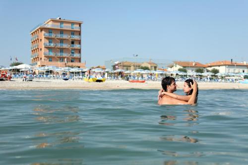 a man and a woman standing in the water at the beach at Abbazia Club Hotel Marotta in Marotta