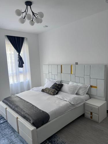 a bedroom with a white bed with a white headboard at Staroot residency in Nairobi