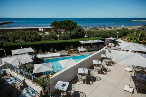 a resort with a pool and tables and umbrellas at Hôtel La Plage 5 étoiles La Grande Motte in La Grande-Motte