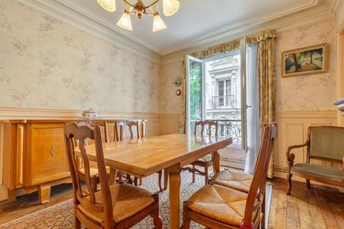 une salle à manger avec une table et des chaises en bois dans l'établissement Chanzy-Spacieux appartement familial Place de la Nation, à Paris