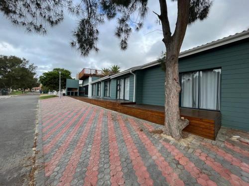 a brick sidewalk next to a building with a tree at Hartenbos Vakansie in Mossel Bay