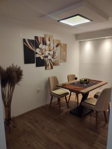 a dining room with a table and chairs and paintings at Gornji Milanovac Apartment in Gornji Milanovac