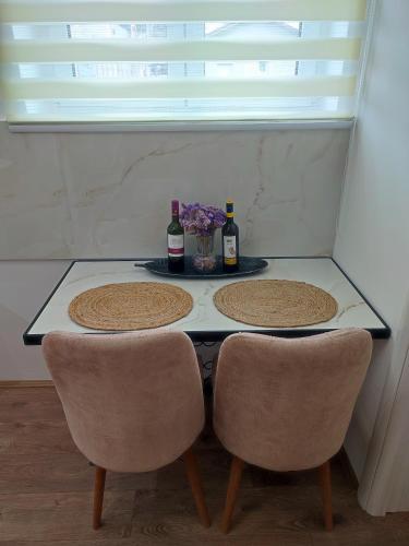 a table with two chairs and two bottles of wine at Gornji Milanovac Apartment in Gornji Milanovac