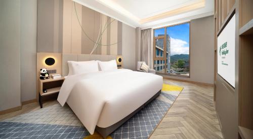 a large white bed in a room with a large window at Holiday Inn Dujiangyan Ancient Town by IHG in Dujiangyan