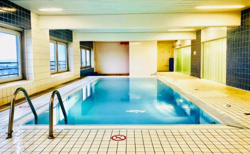 a swimming pool with blue water in a building at DOMspitzen-BLICK, cooles 2 Zimmer Apt mit Indoor-Swimmingpool auf dem Dach, Küche und Smart-TV in Cologne