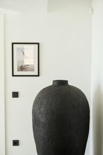 a black vase on a white wall with a picture at Villa Aqua Marine in Kalafatis
