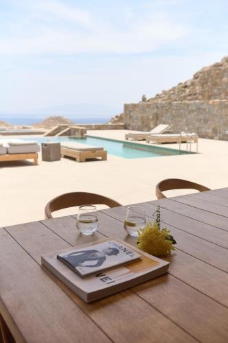a wooden table with a wine glass and a book on it at Villa Aqua Marine in Kalafatis