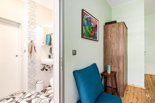 ein Badezimmer mit einem blauen Stuhl und einem Waschbecken in der Unterkunft Luxury And Spacious Apartment at the Hearth of the City in Sofia
