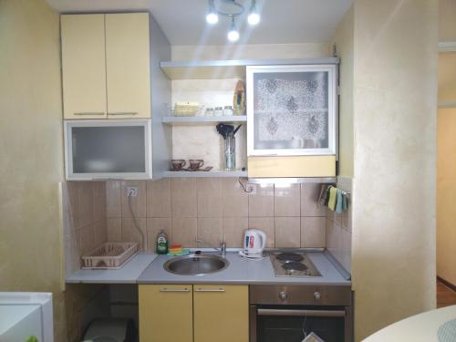a small kitchen with yellow cabinets and a sink at Lea Beo in Belgrade