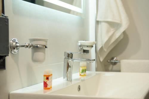 a bathroom sink with a faucet and a mirror at Olivium Rooms in Vlorë