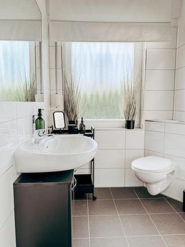a white bathroom with a sink and a toilet at Auszeit - Detmold in Detmold