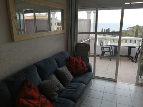 - un canapé bleu dans le salon avec balcon dans l'établissement duplex atypique avec magnifique vue mer et baie d'Agay, à Saint-Raphaël