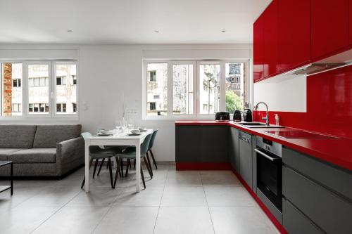 - une cuisine avec des placards rouges, une table et un canapé dans l'établissement Appartement Brivi - Welkeys, à Lille