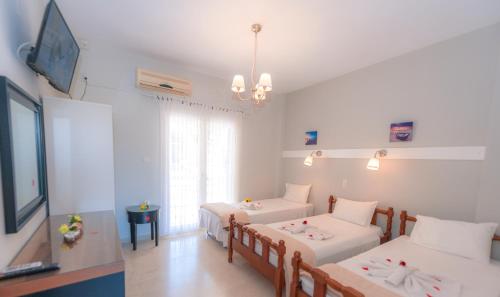 a room with two beds and a flat screen tv at Vassilis Paradise Garden Aparthotel in Agios Georgios Pagon