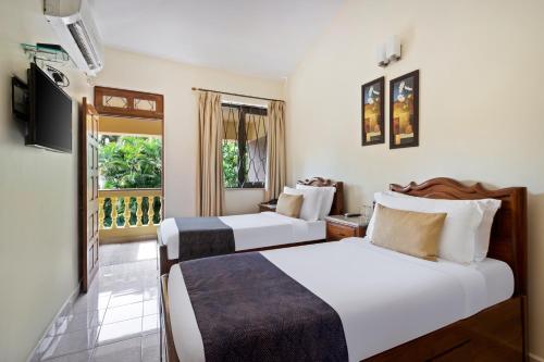 a hotel room with two beds and a window at De Mandarin Beach Resort Suites & Villas, Candolim in Candolim