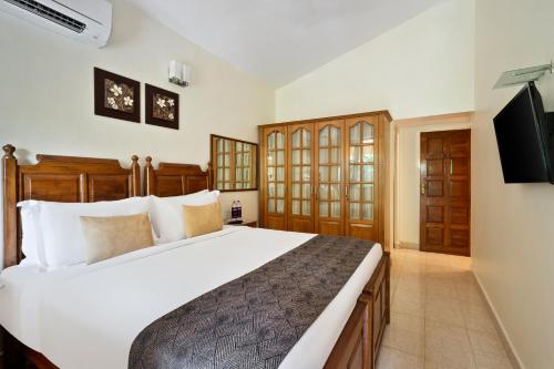 a bedroom with a large bed and a flat screen tv at De Mandarin Beach Resort Suites & Villas, Candolim in Candolim