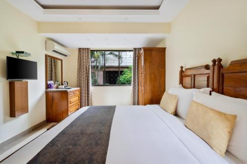 a bedroom with a large white bed and a window at De Mandarin Beach Resort Suites & Villas, Candolim in Candolim