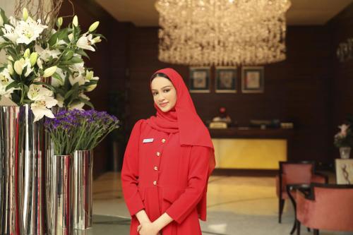a woman in a red hijab standing next to flowers at Kempinski Al Othman Hotel Al Khobar in Al Khobar
