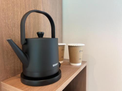 a black tea kettle on a wooden shelf with two cups at Hotel Ganwoljae in Ulsan
