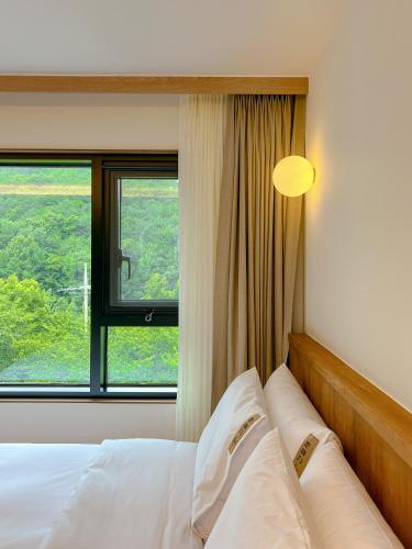 a bedroom with a bed with a large window at Hotel Ganwoljae in Ulsan