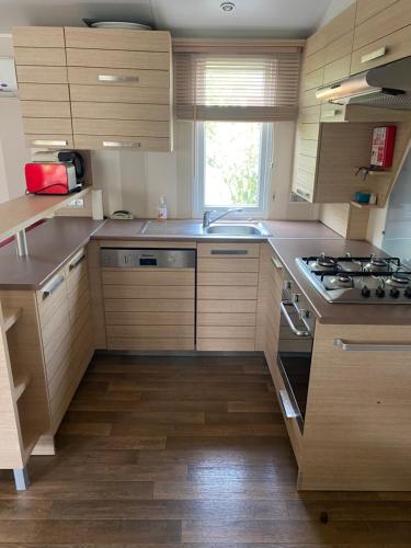 une cuisine avec des armoires en bois et un four à plaques de cuisson dans l'établissement Mobil Home dans le camping 4 étoiles le Montourey, à Fréjus