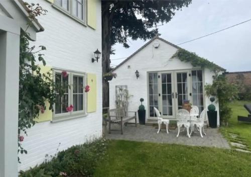 ein weißes Haus mit Tischen und Stühlen im Hof in der Unterkunft Thimble Cottage in Buckinghamshire